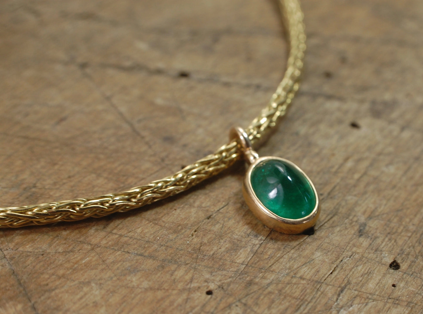 Emerald Cabochon on Handmade Woven 18k gold chain This clear emerald cabochon is bezel-set in 18k gold and suspended from a handmade woven chain of 18k gold in ancient Viking knit. A forged hook clasp finishes this simple and elegant design. Emerald Caboc