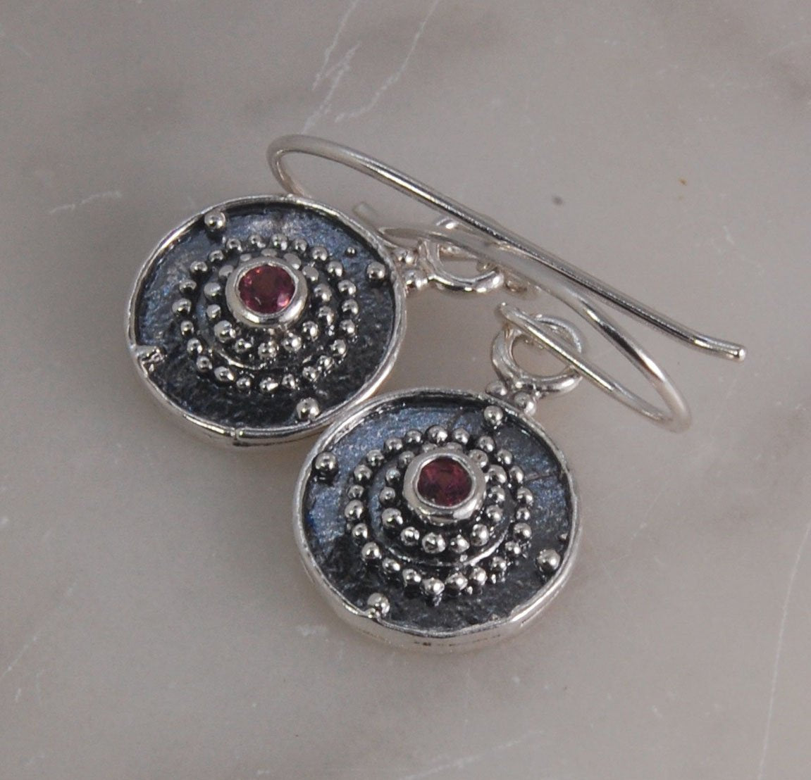 Dangle Shield Earrings in Sterling with Pink Garnet, Red Garnet, Blue Topaz, Peridot, or Amethyst These terrific shield earrings are cast from a granulated original. and is cast using the lost wax process. You can choose which stone to set in your sterlin