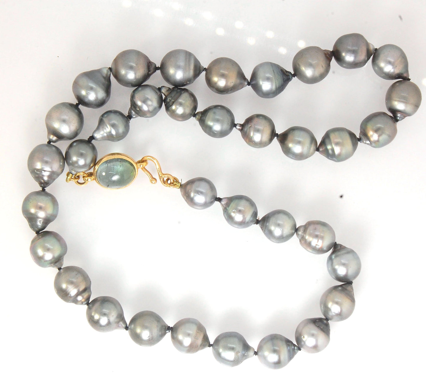 Grey Baroque South Sea Pearl Strand with 18k gold and Tourmaline Clasp This amazingly luminous strand of Grey Baroque South Sea Pearls are 8-10mm each and the strand is slightly graduated. An amazing Bi-color Blue Green Tourmaline cabochon set in 18k with