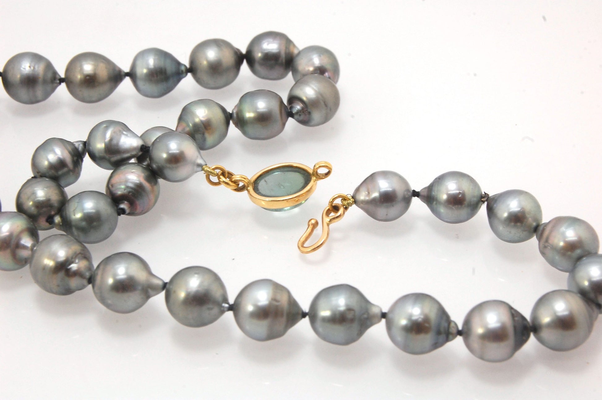 Grey Baroque South Sea Pearl Strand with 18k gold and Tourmaline Clasp This amazingly luminous strand of Grey Baroque South Sea Pearls are 8-10mm each and the strand is slightly graduated. An amazing Bi-color Blue Green Tourmaline cabochon set in 18k with