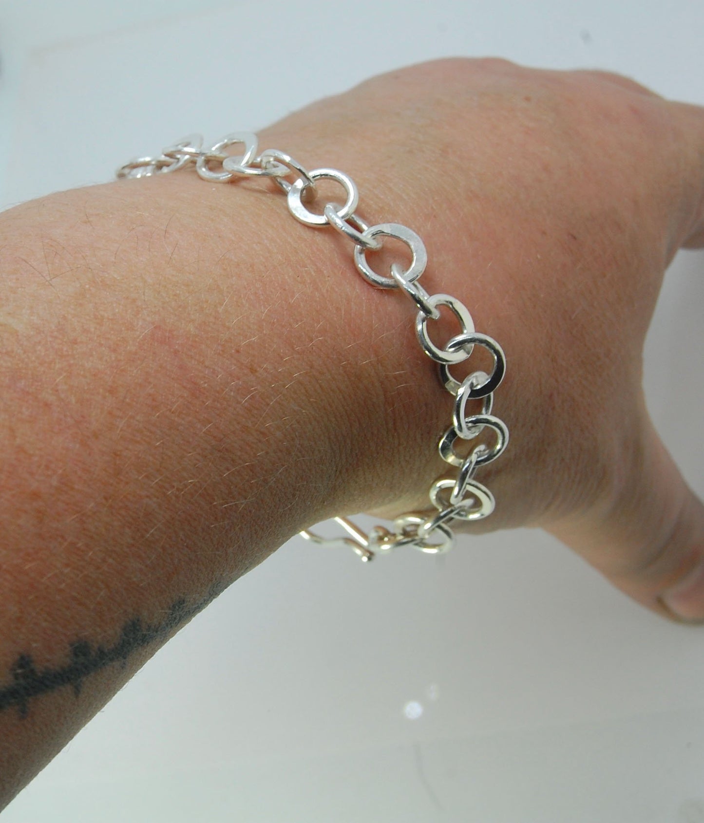 Moonshaped Silver Hammered Link Bracelet These are fun and eye-catching silver bracelets! They have a nice weight without being heavy. Each link is soldered and hammered in a moon pattern for a shimmery look. Each has a forged hook clasp. Each link is for