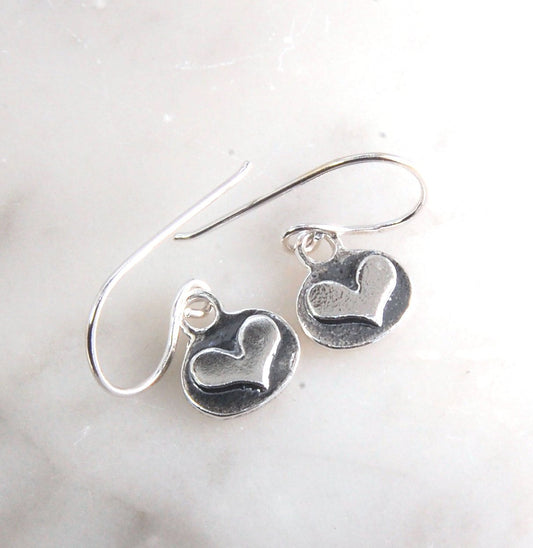 Heart Dangle Earrings These terrific heart dangle earrings are cast from a granulated original and are cast using the lost wax process. I cut out a heart of fine silver and fused it to an oval background using the ancient fusing process of granulation.Gra