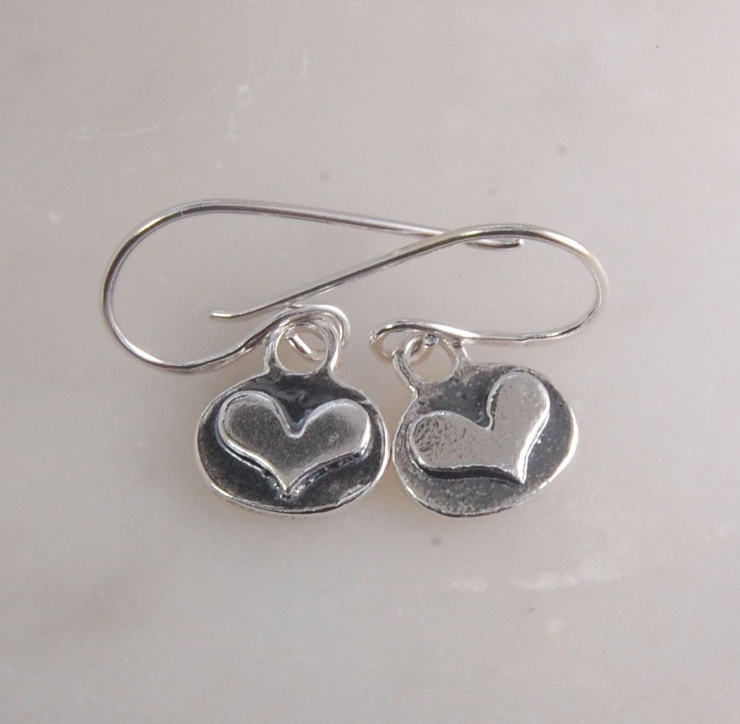 Heart Dangle Earrings These terrific heart dangle earrings are cast from a granulated original and are cast using the lost wax process. I cut out a heart of fine silver and fused it to an oval background using the ancient fusing process of granulation.Gra