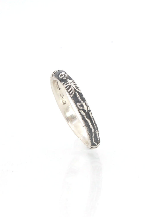 Oxidized Memento Mori Skeleton Ring - 3.3mm - Sterling silver This is the second-most narrow of my Memento Mori rings at 3.3mm wide. This is the cute skeleton with the shy knees! The Skeleton is flanked by intertwined hearts on one side and about 1/2 of t