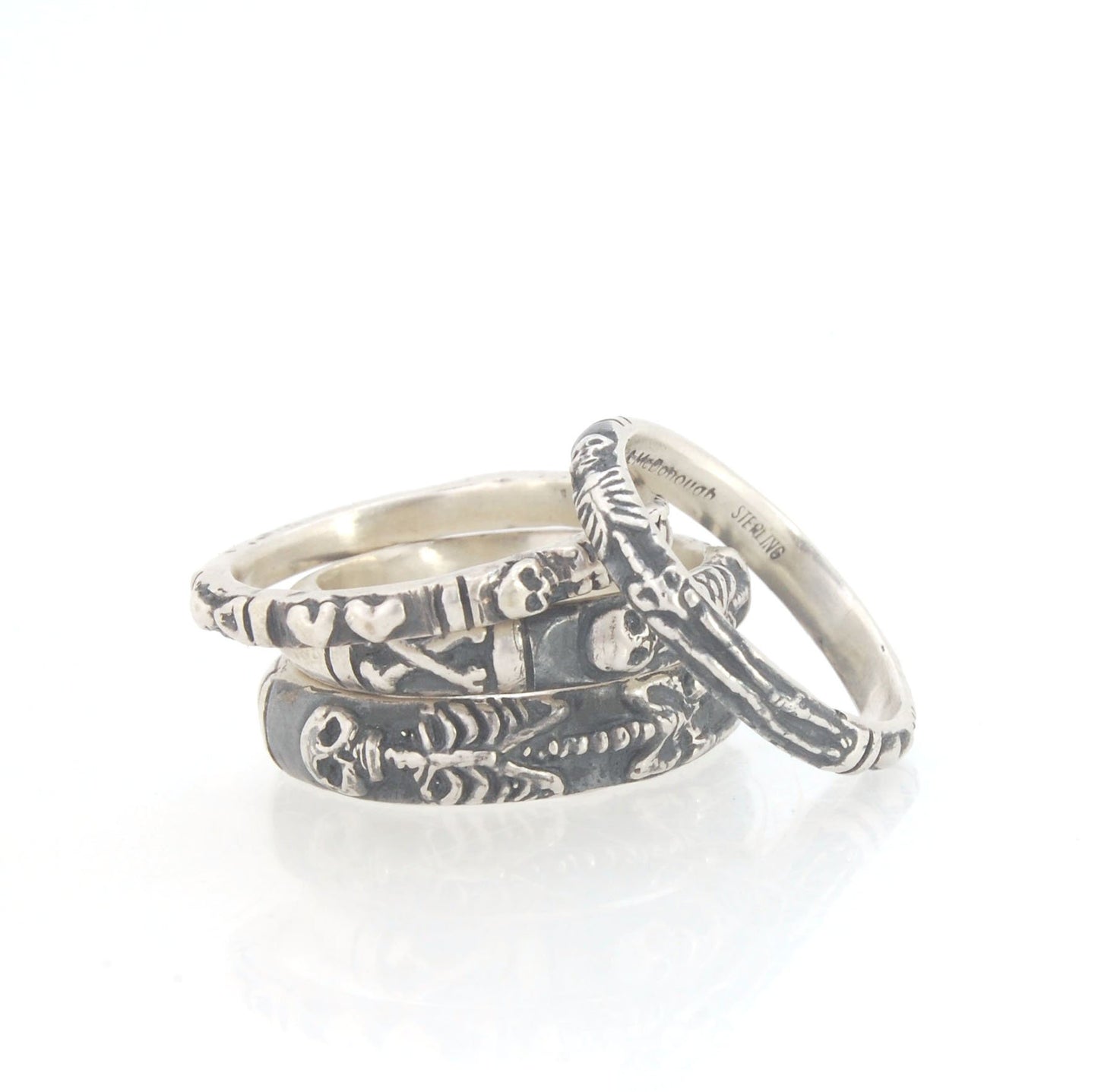 Oxidized Memento Mori Skeleton Ring - 3.3mm - Sterling silver This is the second-most narrow of my Memento Mori rings at 3.3mm wide. This is the cute skeleton with the shy knees! The Skeleton is flanked by intertwined hearts on one side and about 1/2 of t