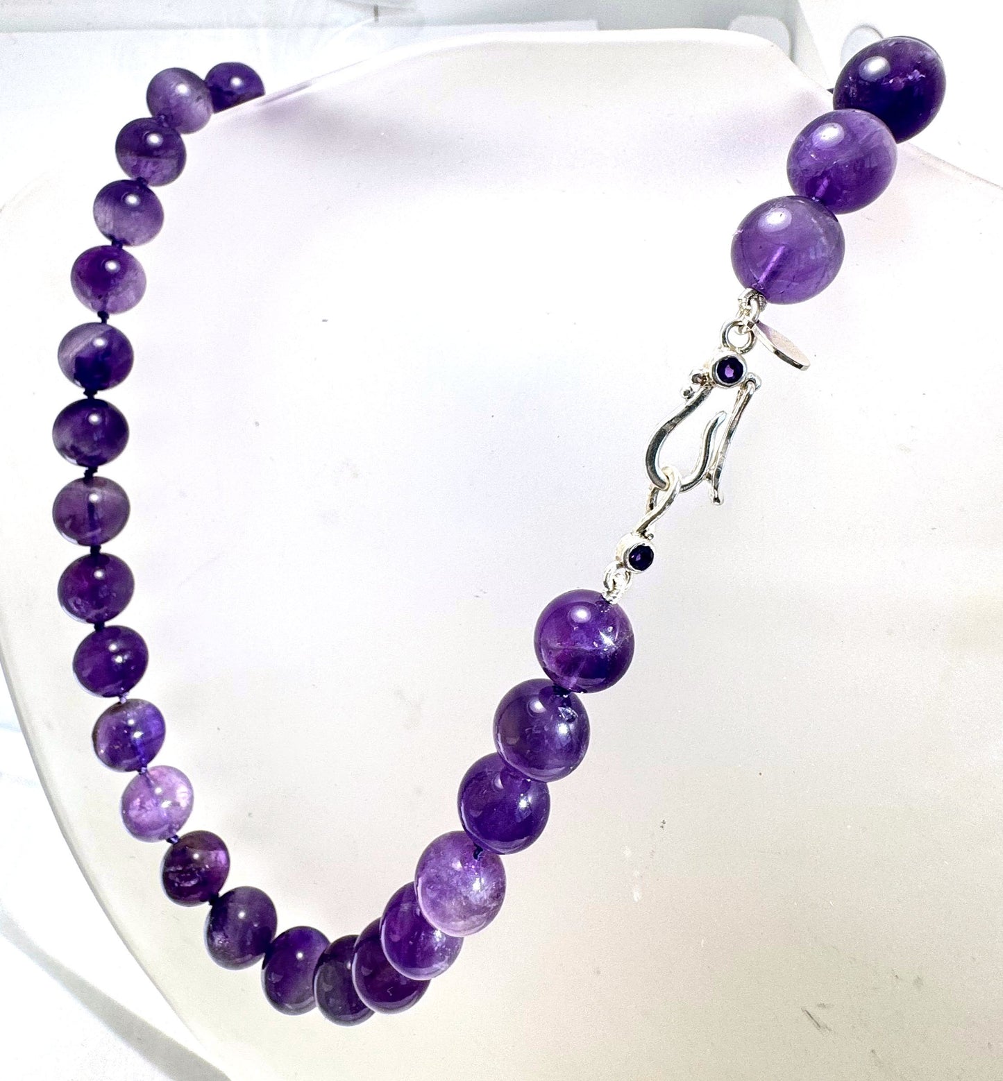 Round Amethyst Gemstone Knotted Strand These lovely round Amethyst Gemstone Beads are a large 11.5mm! These beauties have a nice weight and warmth and are knotted on silk like pearls. I have made a sterling silver two-part clasp with faceted amethysts and