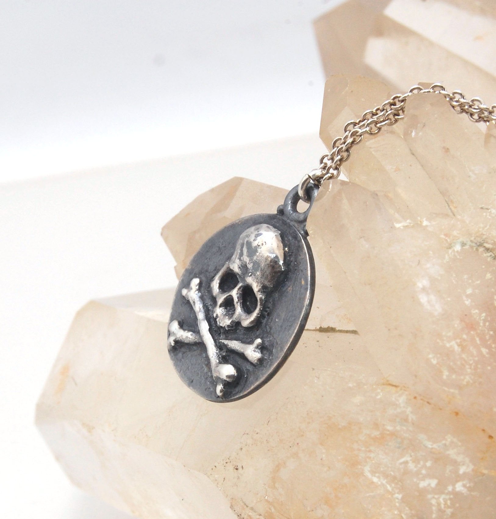 Skullbones Coin Pendant This solid sterling silver Skulbones coin pendant is wax carved by hand and cast using the ancient process of Lost Wax casting. I then made a mold, which I can inject with wax and make wax copies of the Skull and Crossbones Coin an