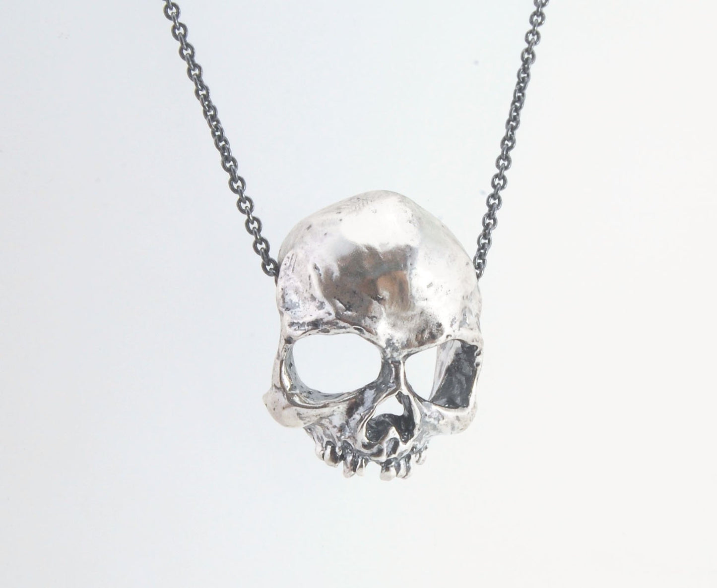 Through the Veil Darkly Skull Face Slider Necklace This Through the Veil Darkly Skull Face pendant in Sterling Silver has a lot of expression and a nice weight with an oxidized sterling silver chain passing thorugh the back of the face. It’s not too big o