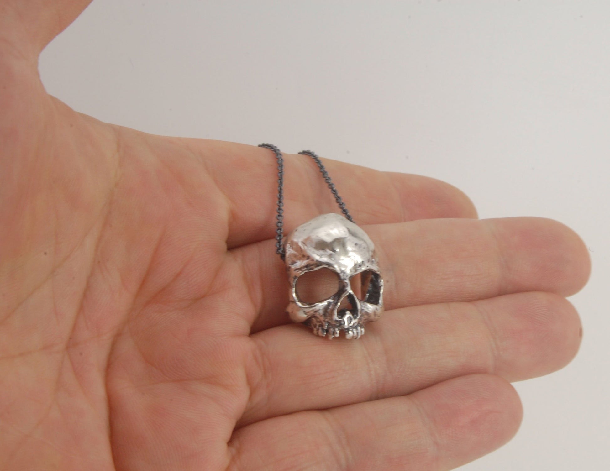 Through the Veil Darkly Skull Face Slider Necklace This Through the Veil Darkly Skull Face pendant in Sterling Silver has a lot of expression and a nice weight with an oxidized sterling silver chain passing thorugh the back of the face. It’s not too big o