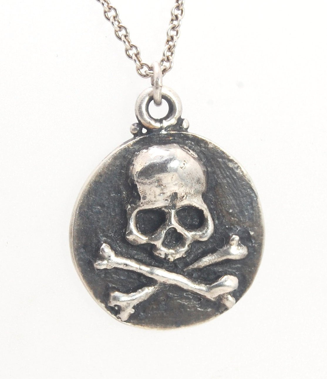 Skullbones Coin Pendant This solid sterling silver Skulbones coin pendant is wax carved by hand and cast using the ancient process of Lost Wax casting. I then made a mold, which I can inject with wax and make wax copies of the Skull and Crossbones Coin an