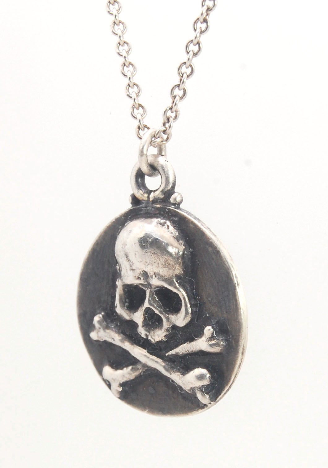 Skullbones Coin Pendant This solid sterling silver Skulbones coin pendant is wax carved by hand and cast using the ancient process of Lost Wax casting. I then made a mold, which I can inject with wax and make wax copies of the Skull and Crossbones Coin an