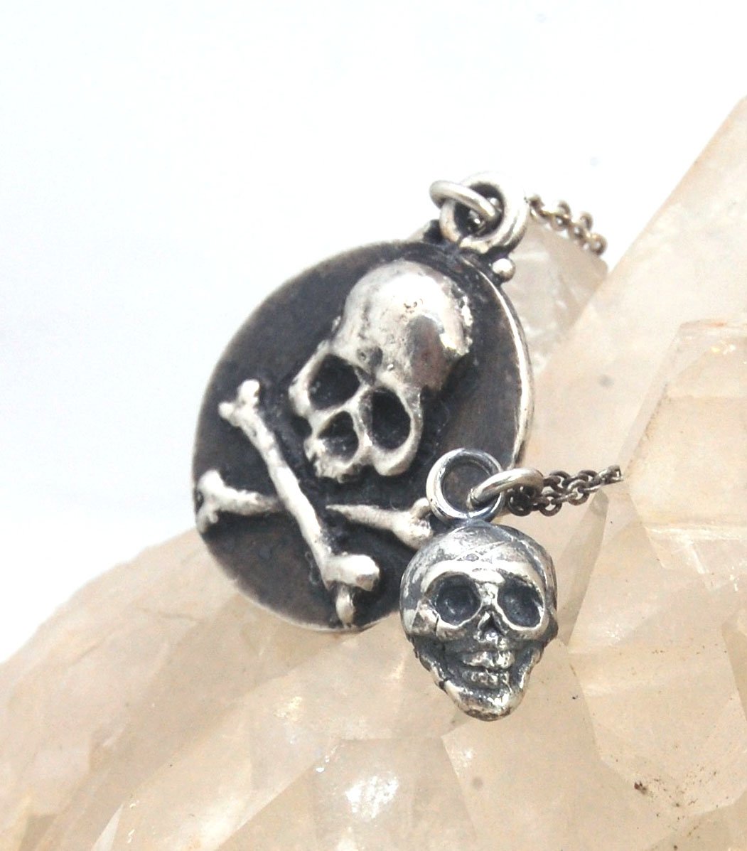 Skullbones Coin Pendant This solid sterling silver Skulbones coin pendant is wax carved by hand and cast using the ancient process of Lost Wax casting. I then made a mold, which I can inject with wax and make wax copies of the Skull and Crossbones Coin an