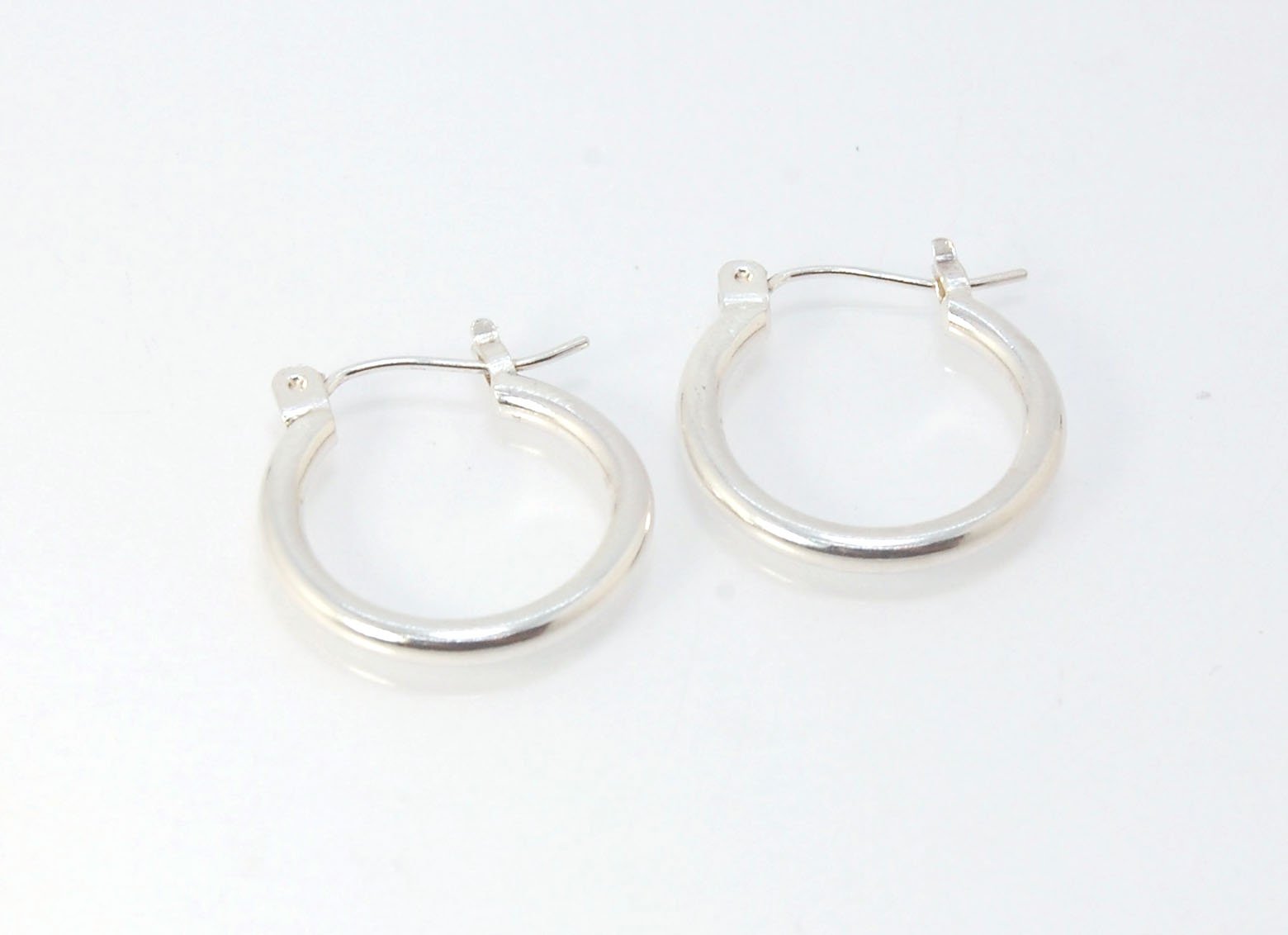 Solid Hoops with clasp in Silver - Medium These hoops are great for everyday wear. Classic and understated at 16mm or about 1/2”.These are made with a solid round rod cut into links and hammered with a clasp ear wire soldered on. Then polished and finishe